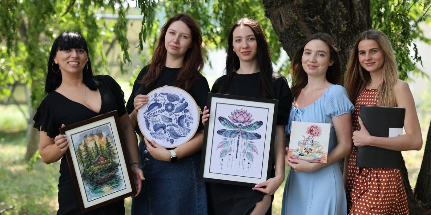 Abris Art designers holding finished bead and cross stitch embroidery works